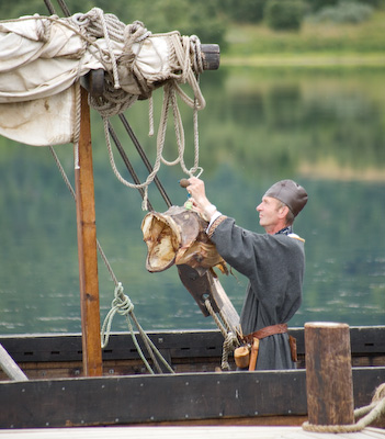 Viking fisherman hanging a dried fish from the yard arm